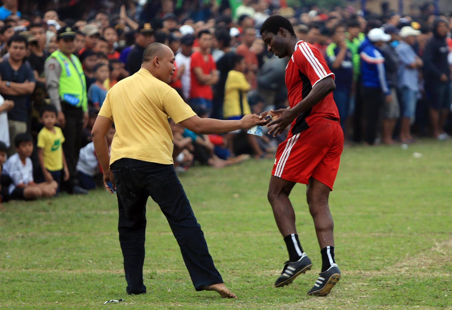 Pemain Portal FC yang juga mantan pemain Arema Malang Emil Mbamba (kanan) menerima saweran uang dari seorang penonton usai mencetak gol pada pertandingan final liga kampung yang berlangsung di lapangan Latus Jaya Ciputat, Tangerang Selatan, Banten, Minggu (14/6). Berhentinya kompetisi di Indonesia akibat dibekukannya PSSI oleh Menpora membuat banyak pesepakbola klub - klub peserta ISL yang mengikuti Tarkam (pertandingan antar kampung) yang tujuannya untuk menjaga kebugaran dan juga penghasilannya dari sepak bola. ANTARA FOTO/Muhammad Iqbal